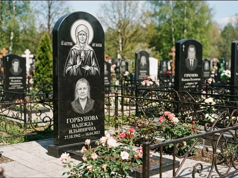 Памятник с гравировкой иконы: стела с арочным верхом и киотом под образ — гравировка образа Матроны Московской, гранитный цоколь с тёмной плиткой, работа «Ковалёв» в Екатеринбурге