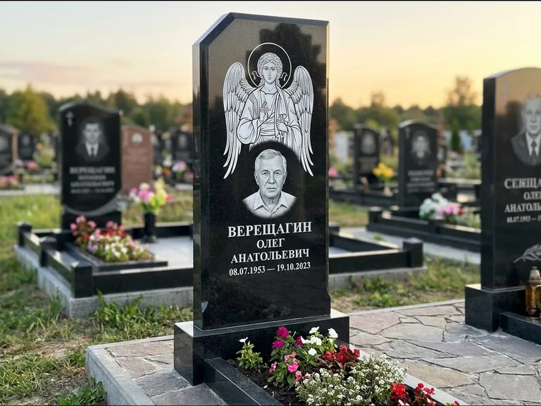 Памятник с гравировкой иконы: стела с резным навершием и нимбом в золоте — гравировка образа Спасителя, высокие разросшиеся туи полукругом, работа «Мельникова» в Екатеринбурге