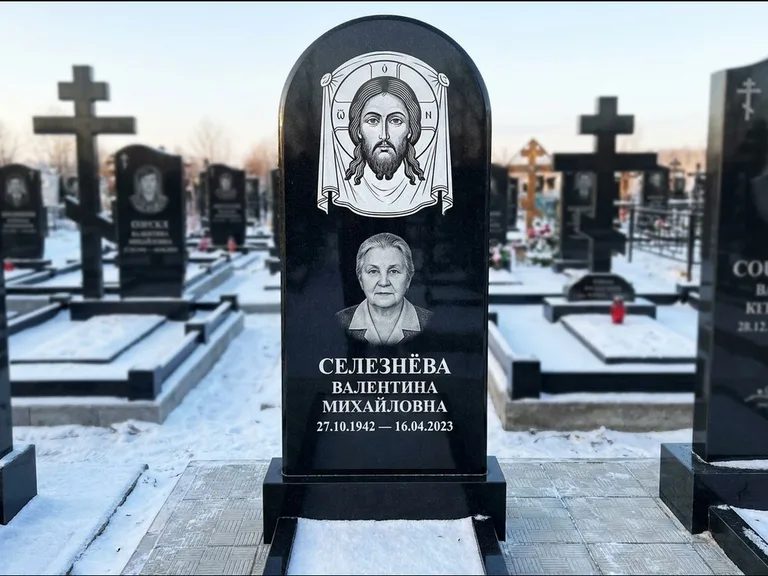 Памятник с гравировкой иконы: небольшая скромная одиночная стела с именной иконой — золочёный нимб на образе, аккуратный участок с газоном, работа «Ковалёв» в Екатеринбурге