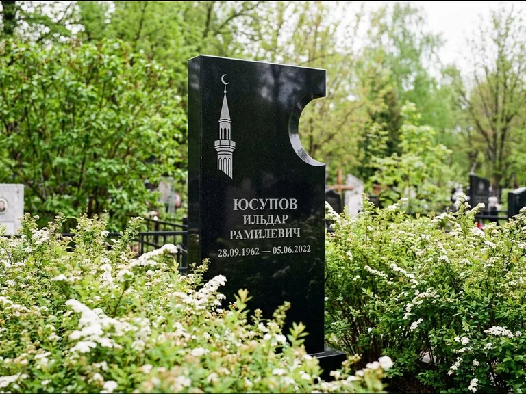 Мусульманский памятник с гравировкой мечети: стела с боковым вырезом в форме полумесяца — гравировка минарета с полумесяцем, низкие кусты спиреи в цвету, работа «Юсупов» в Екатеринбурге