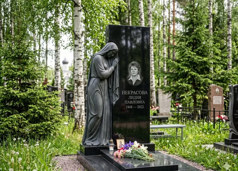 Гранитная фигура скорбящего мужчины у чёрной стелы в Екатеринбурге